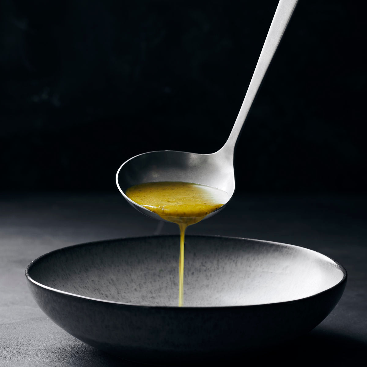 A steel soup ladle with a hole at the top of the handle to hang it up.