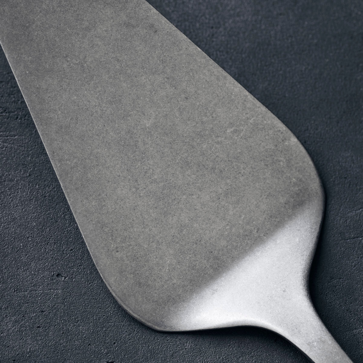 A stainless steel cake server with a hole in the top of the handle for hanging up after use.