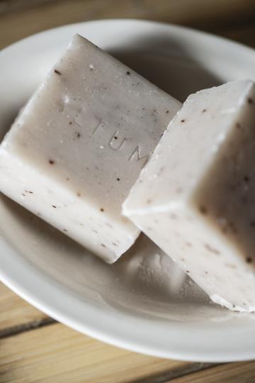 Two part ceramic soap dish. Oval shaped and cream coloured. The top part lifts out and has holes that let water drain. Close up with soap.