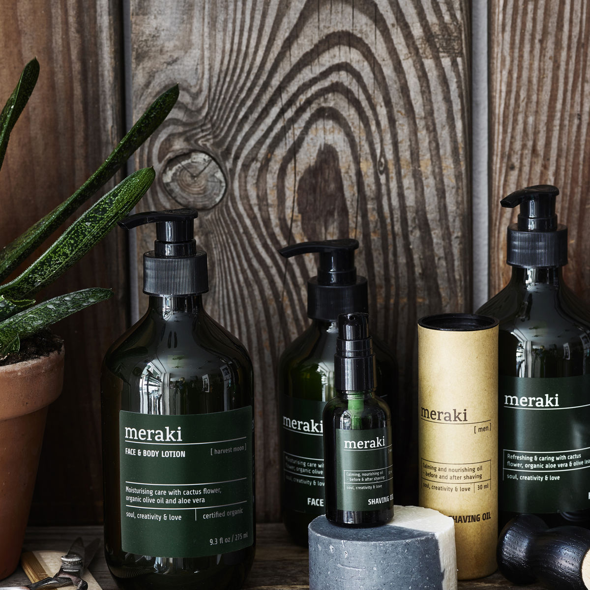 A dark green bottle with black pump and a label that says 'Meraki Face & Body Lotion'