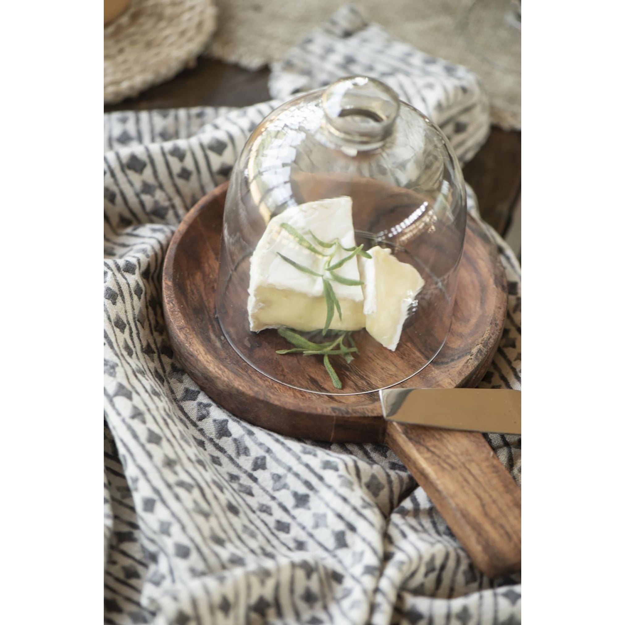 a round wooden dish made from a deep amber acacia wood, with a short handle.