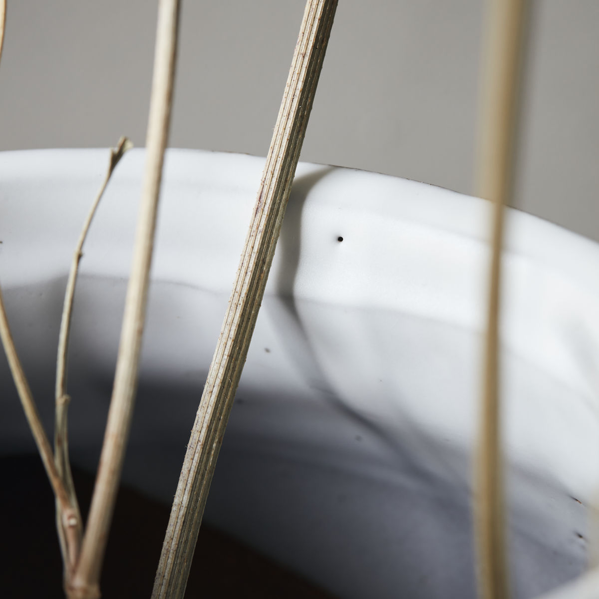 A clay vase glazed in white, with a larger circular base and smaller version of the same shape on top.