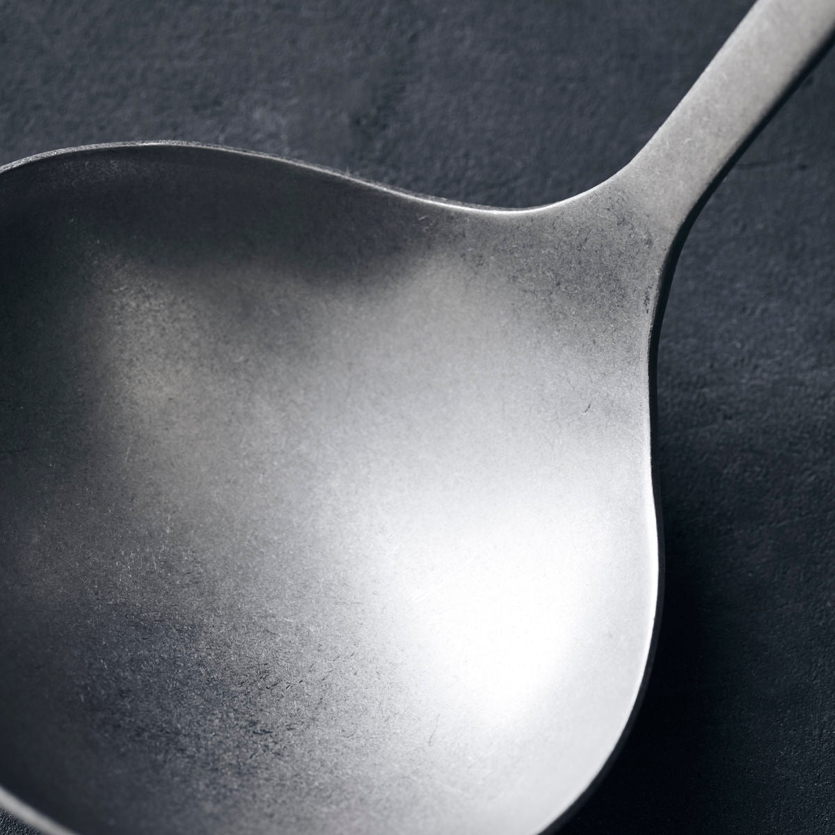 A steel soup ladle with a hole at the top of the handle to hang it up.