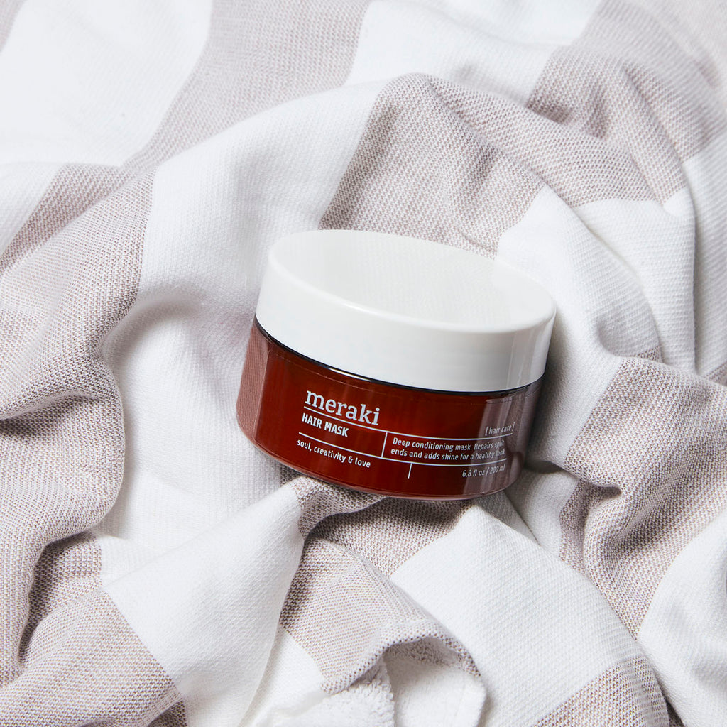 A deep conditioning hair mask in a round tub, brown with a white lid.