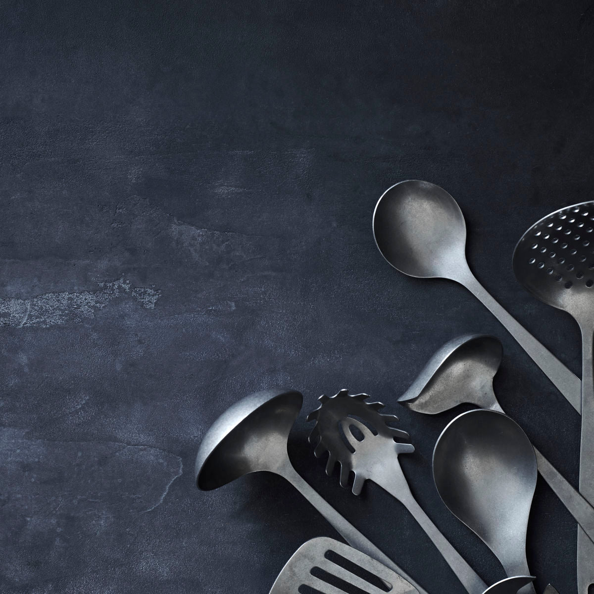 A stainless steel serving spoon, rounded with a long handle and a hole in the end of the handle to hang up the spoon on a hook.