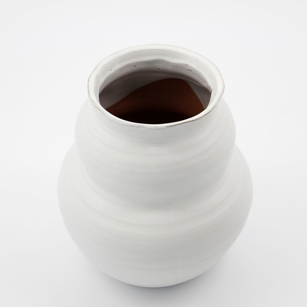 A clay vase glazed in white, with a larger circular base and smaller version of the same shape on top.